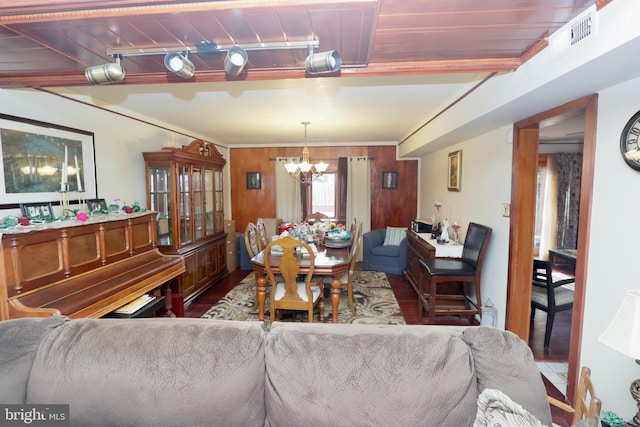 living room featuring crown molding, a notable chandelier, wood-type flooring, and wood walls