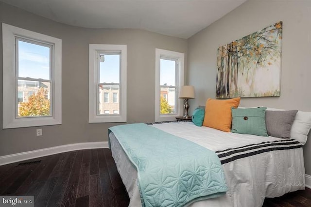 bedroom with dark hardwood / wood-style flooring and multiple windows