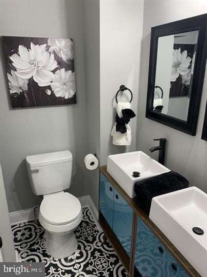 bathroom with toilet, vanity, and tile patterned flooring