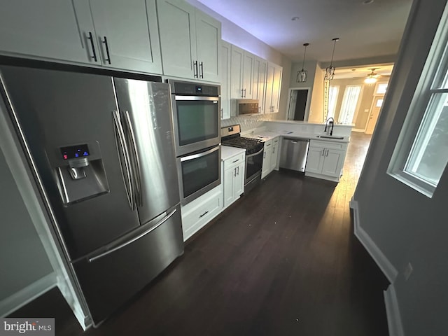 kitchen featuring stainless steel appliances, backsplash, dark wood-type flooring, pendant lighting, and white cabinets