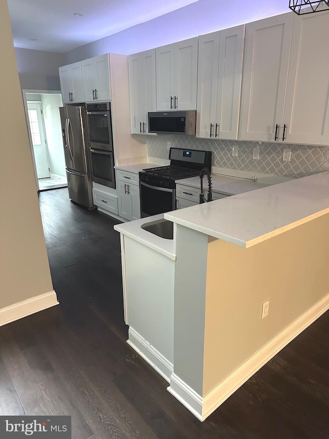 kitchen with backsplash, kitchen peninsula, dark wood-type flooring, a breakfast bar area, and stainless steel appliances