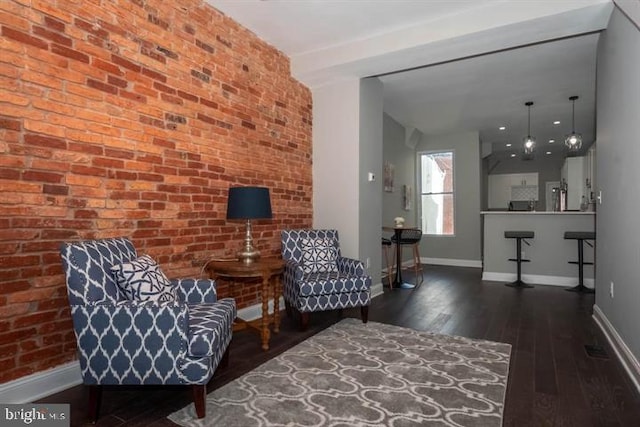 living area with dark wood-type flooring and brick wall