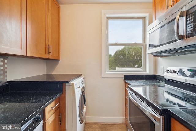 kitchen with dishwashing machine, dark stone countertops, stove, washer / clothes dryer, and backsplash