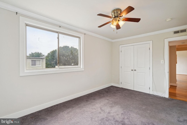 unfurnished bedroom with ceiling fan, carpet flooring, a closet, and ornamental molding