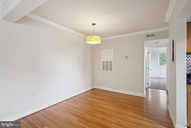 spare room featuring wood-type flooring and ornamental molding