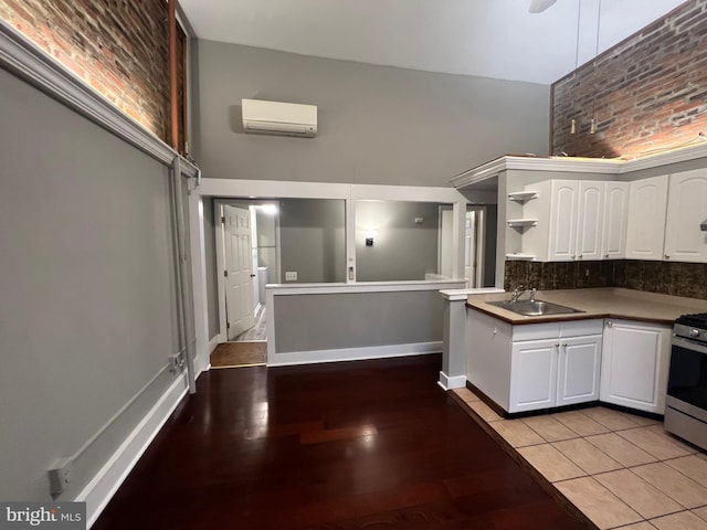 kitchen featuring light tile patterned flooring, white cabinets, sink, a wall mounted AC, and stainless steel gas range oven