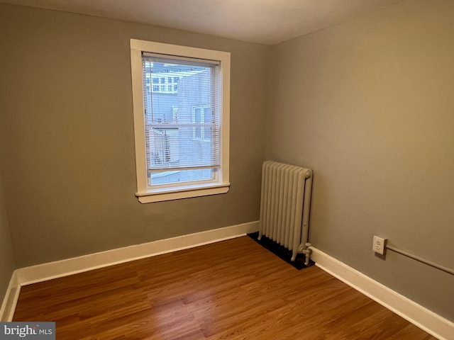 unfurnished room with radiator heating unit and hardwood / wood-style floors