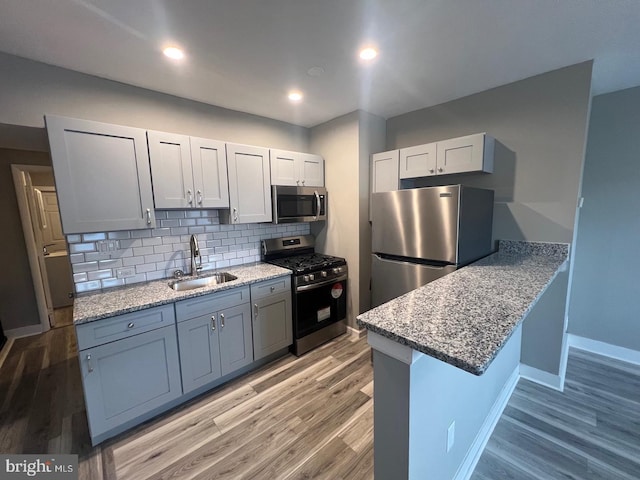 kitchen with a kitchen bar, kitchen peninsula, appliances with stainless steel finishes, tasteful backsplash, and sink