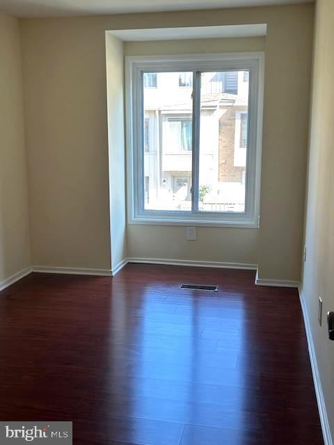 empty room with plenty of natural light and dark hardwood / wood-style flooring