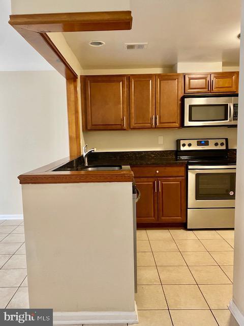 kitchen featuring stainless steel appliances, sink, and light tile patterned floors