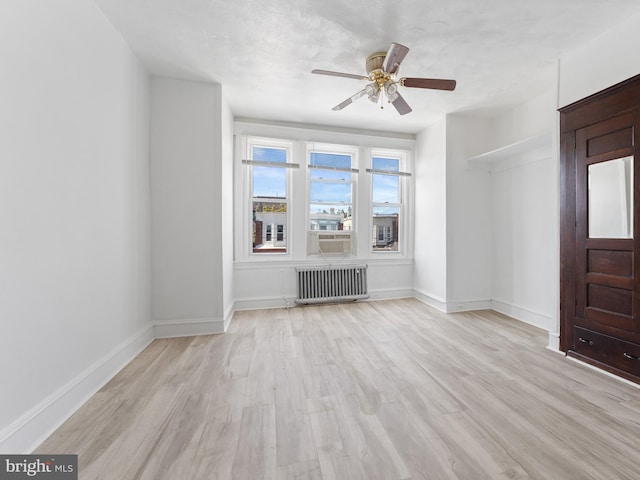 unfurnished living room featuring light wood-type flooring, ceiling fan, and radiator heating unit