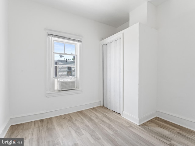 unfurnished bedroom featuring cooling unit and light hardwood / wood-style flooring