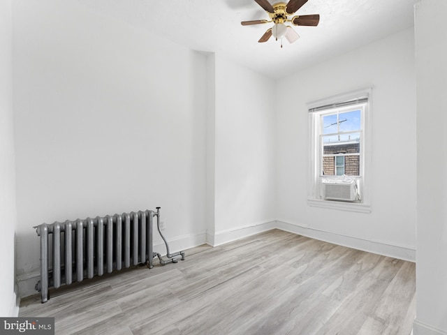 empty room featuring ceiling fan, radiator, cooling unit, and light hardwood / wood-style floors