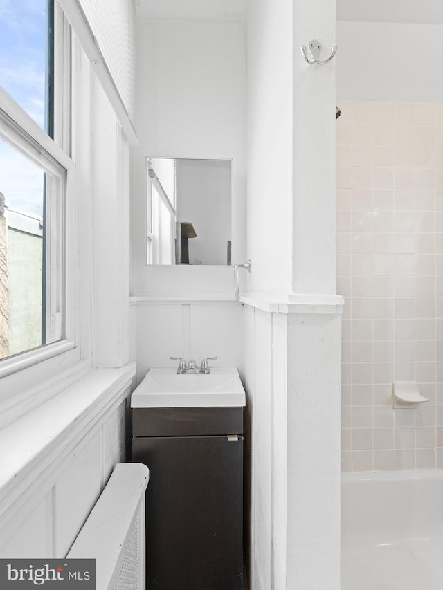 bathroom with tiled shower / bath combo, vanity, and radiator heating unit