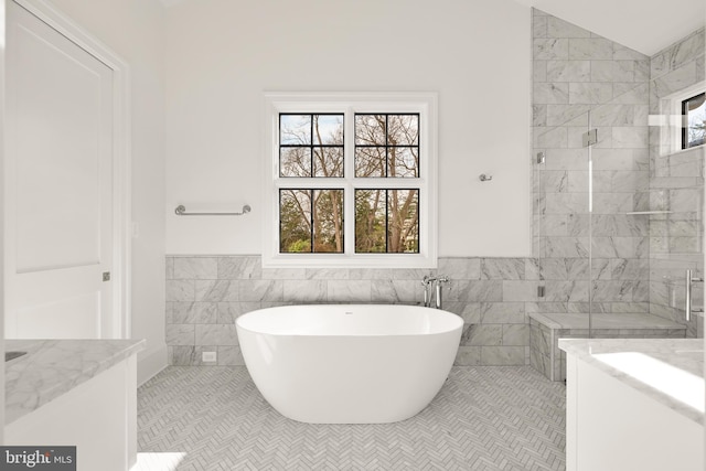 bathroom with lofted ceiling, vanity, tile walls, and tile patterned floors