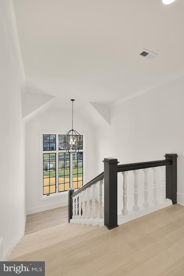 hallway with a notable chandelier, an upstairs landing, visible vents, vaulted ceiling, and light wood finished floors