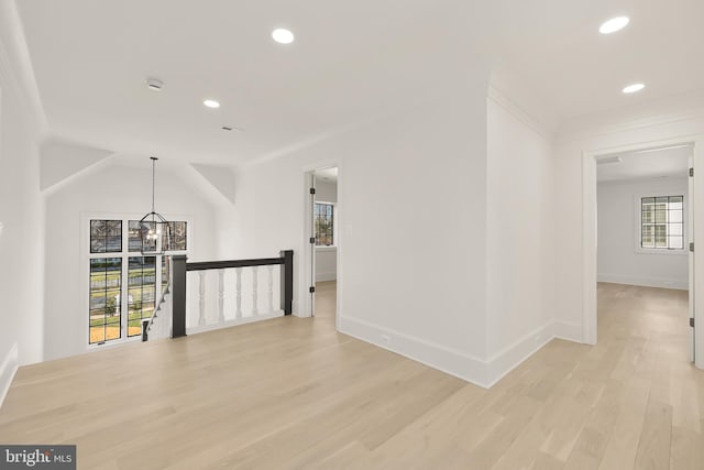 hallway with vaulted ceiling, light hardwood / wood-style flooring, and a notable chandelier