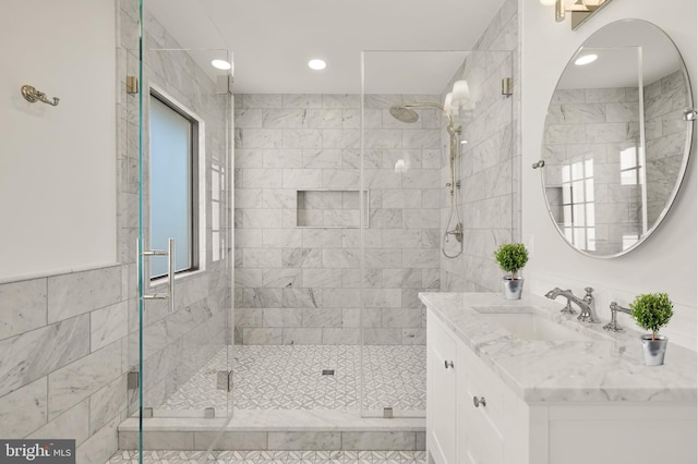 bathroom with tile walls, a shower stall, vanity, and recessed lighting