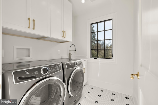 laundry area with cabinets, tile patterned floors, separate washer and dryer, and sink