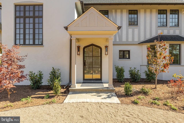 property entrance featuring roof with shingles and stucco siding