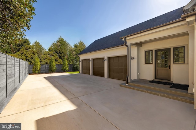 garage featuring fence and concrete driveway