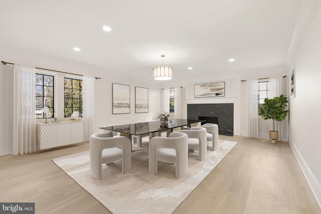 dining area featuring a high end fireplace and light hardwood / wood-style flooring