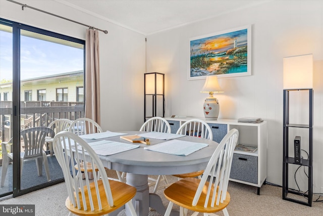 carpeted dining space featuring crown molding