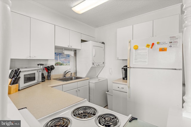 kitchen featuring white cabinetry, stacked washer and dryer, white appliances, and sink