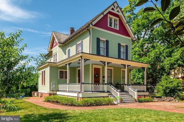 victorian house featuring covered porch and a front lawn