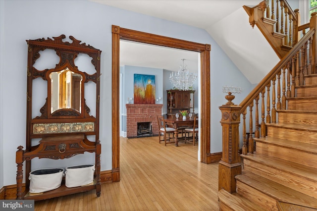 entryway featuring a fireplace, vaulted ceiling, light hardwood / wood-style flooring, and a chandelier