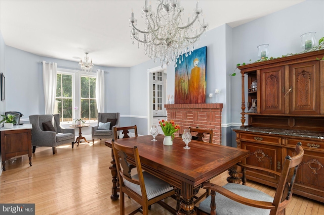 dining area featuring a notable chandelier, light hardwood / wood-style flooring, and a fireplace