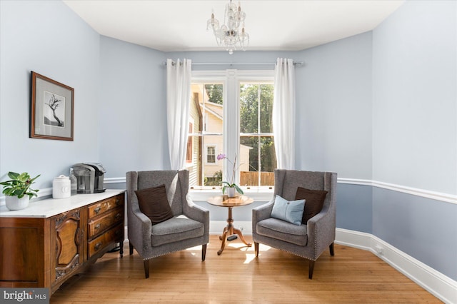 sitting room featuring a notable chandelier and light wood-type flooring