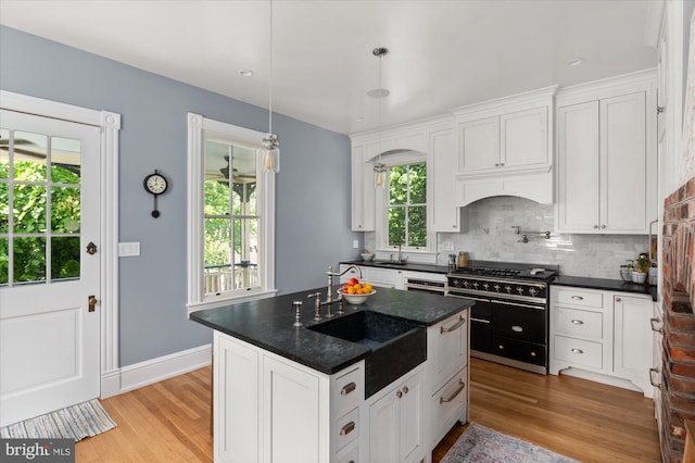 kitchen featuring white cabinets, a center island, light hardwood / wood-style floors, decorative light fixtures, and double oven range