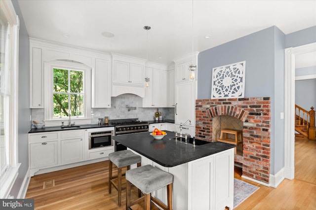 kitchen featuring white cabinetry, a fireplace, light hardwood / wood-style flooring, and tasteful backsplash