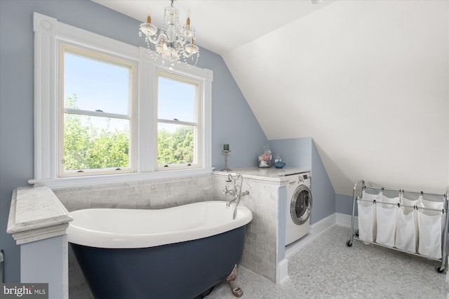 bathroom featuring washer / clothes dryer, an inviting chandelier, lofted ceiling, and a bath