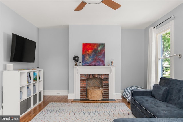 living room featuring a fireplace, wood-type flooring, and ceiling fan