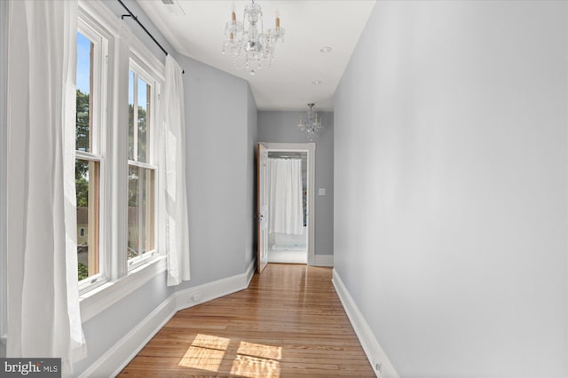 hallway featuring light wood-type flooring and a chandelier