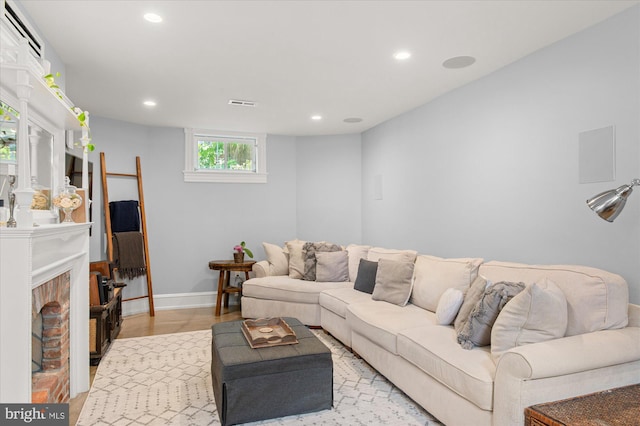 living room featuring a brick fireplace and light wood-type flooring