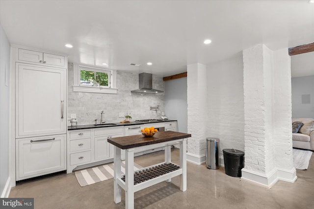 kitchen featuring white cabinetry, wall chimney exhaust hood, sink, stainless steel gas cooktop, and backsplash