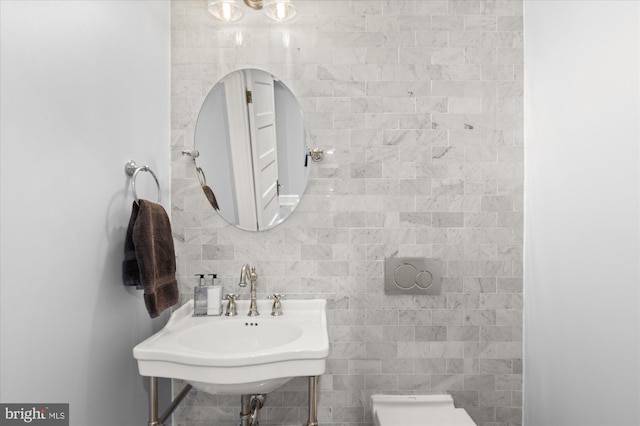 bathroom with tile walls, toilet, and sink