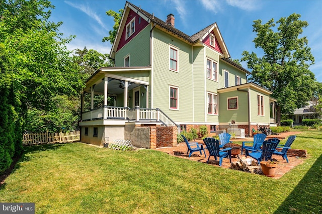 rear view of house featuring a yard and an outdoor fire pit