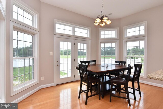 dining area with a notable chandelier, a wealth of natural light, and light wood-type flooring