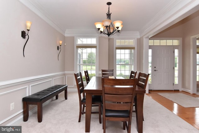 dining space with ornamental molding, a notable chandelier, and light hardwood / wood-style floors