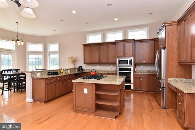 kitchen featuring light hardwood / wood-style flooring, an inviting chandelier, kitchen peninsula, and stainless steel appliances