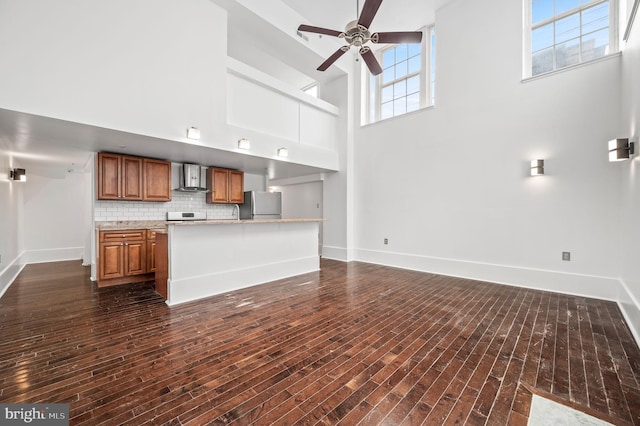 unfurnished living room with dark hardwood / wood-style floors, ceiling fan, and a high ceiling