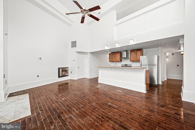 unfurnished living room featuring ceiling fan, sink, dark hardwood / wood-style floors, and high vaulted ceiling