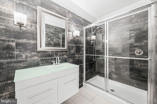 bathroom with tile walls, walk in shower, vanity, and tile patterned flooring