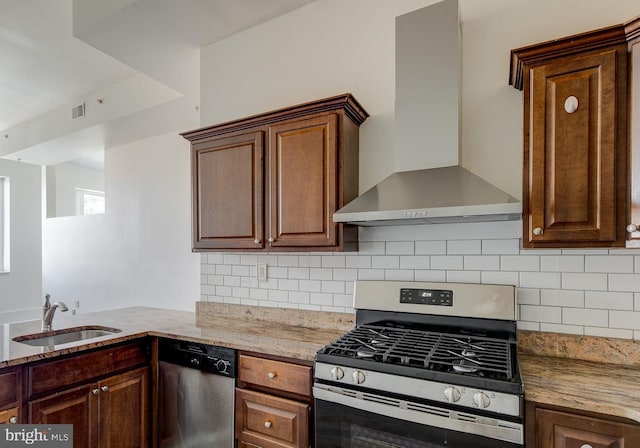 kitchen featuring decorative backsplash, sink, appliances with stainless steel finishes, wall chimney exhaust hood, and light stone counters