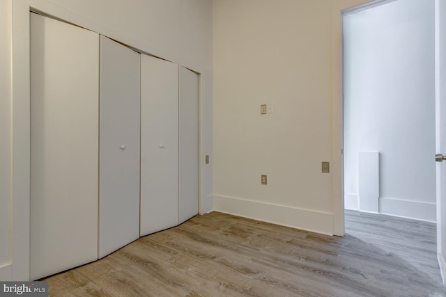 unfurnished bedroom featuring light wood-type flooring and a closet