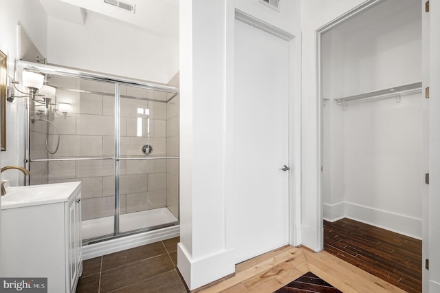 bathroom with walk in shower, vanity, and wood-type flooring